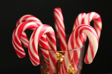 Photo of Christmas candy canes in glass on black background, closeup
