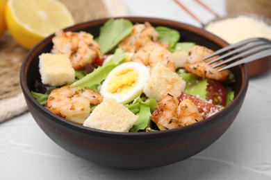 Delicious Caesar salad with shrimps and fork served on white table, closeup