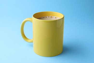 Photo of Yellow mug of freshly brewed hot coffee on light blue background