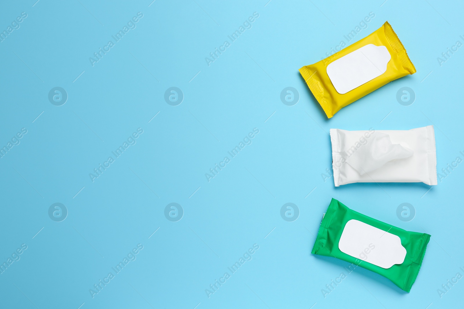 Photo of Wet wipes flow packs on light blue background, flat lay. Space for text