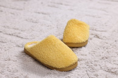 Photo of Yellow soft slippers on light carpet, closeup