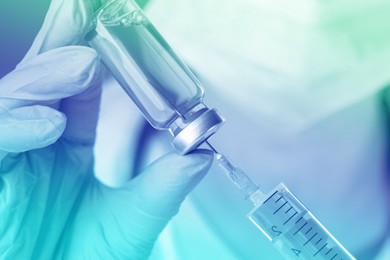 Image of Doctor filling syringe with medication from vial, closeup. Color toned