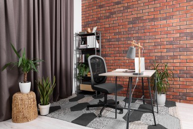 Photo of Stylish workplace with desk, chair, bookcase and potted plants at home