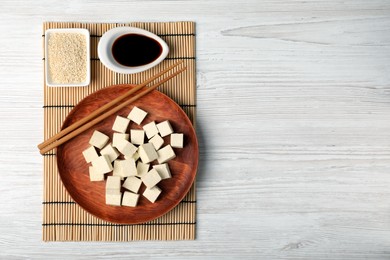 Photo of Delicious tofu with soy sauce and sesame seeds on white wooden table, flat lay. Space for text