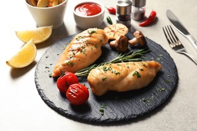 Photo of Slate plate with fried chicken breasts and garnish served on table