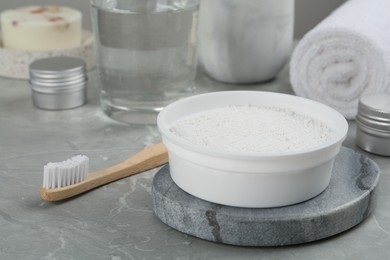 Photo of Tooth powder and brush on light grey marble table, closeup