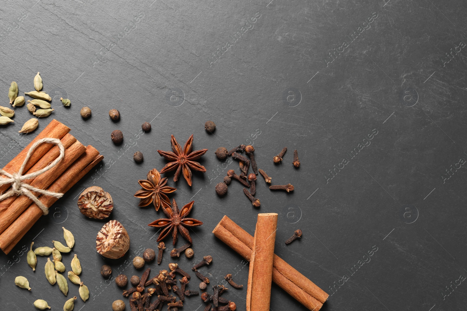 Photo of Different spices on dark gray textured table, flat lay. Space for text