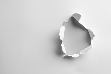Photo of Hole in white paper on light background, space for text