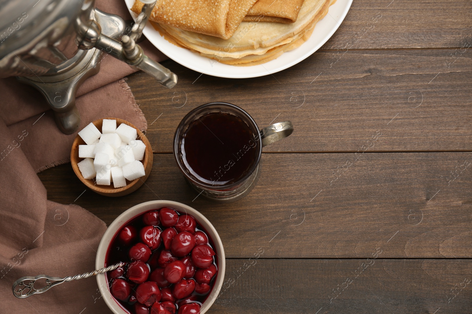 Photo of Metal samovar with cup of tea and treats on wooden table, flat lay. Space for text