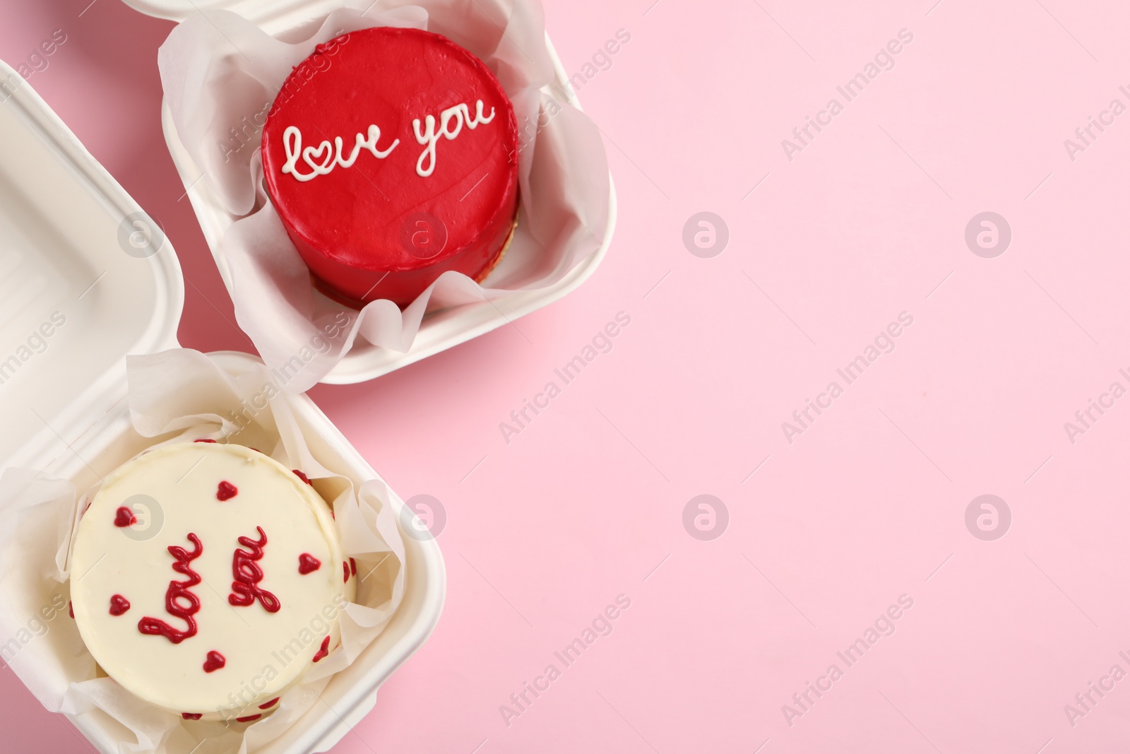 Photo of St. Valentine's day surprise. Bento cakes in takeaway boxes on pink table, flat lay. Space for text