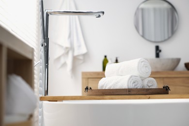 Photo of Rolled bath towels on tub tray in bathroom