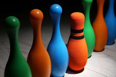 Fabric bowling pin among others on wooden floor, closeup. Diversity concept