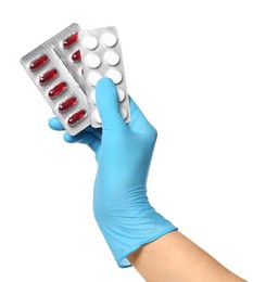 Scientist in protective gloves holding pills on white background, closeup