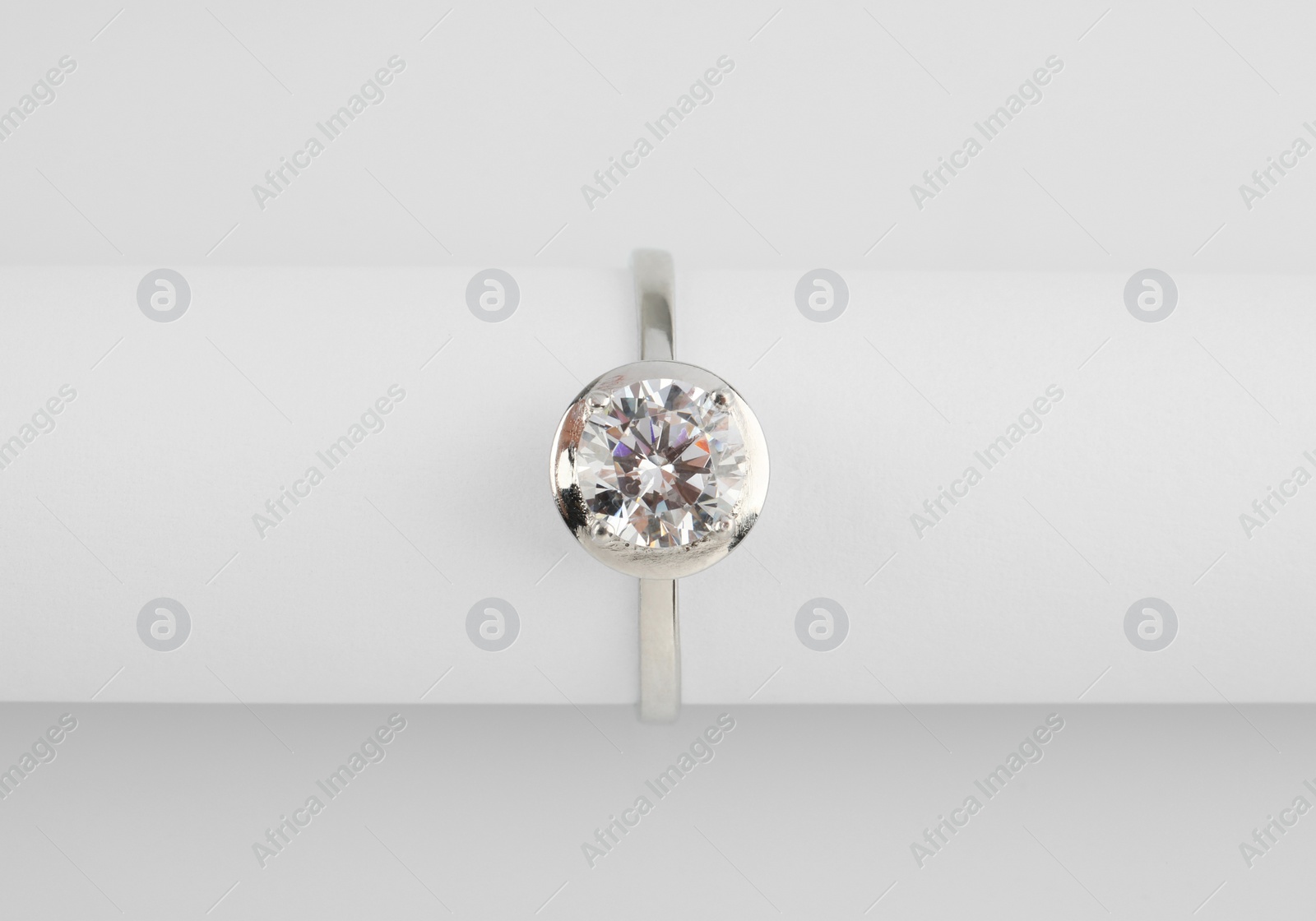 Photo of Beautiful engagement ring with gemstone on white background, top view