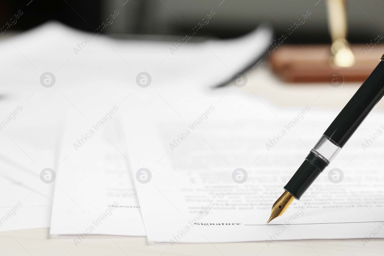 Photo of Signing notary document with fountain pen at light table, closeup. Space for text