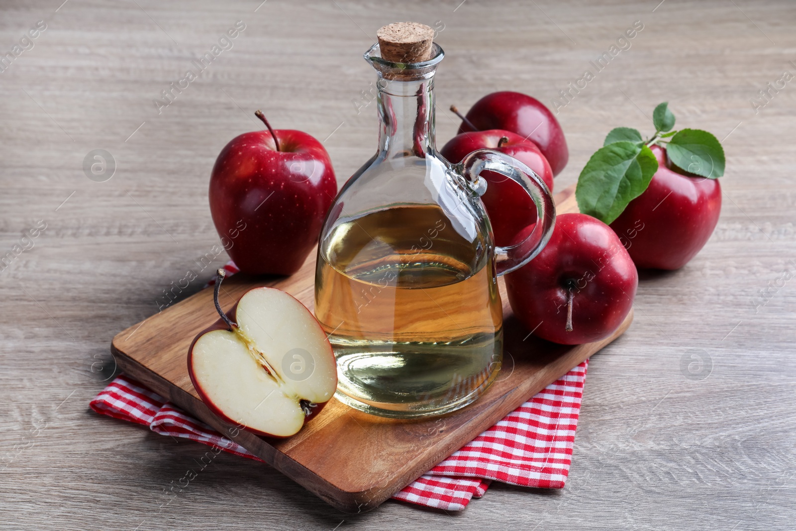 Photo of Jug of tasty juice and fresh ripe red apples on wooden table