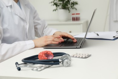 Endocrinologist working at table, focus on stethoscope and model of thyroid gland