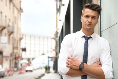 Photo of Portrait of handsome young man on city street. Space for text