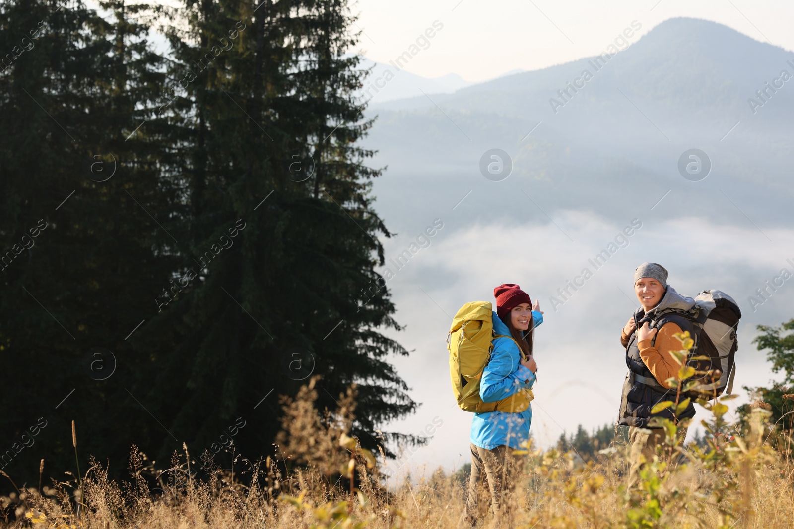 Photo of Tourists with backpacks in mountains on sunny day. Space for text