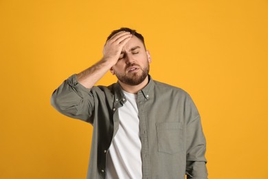 Photo of Man suffering from migraine on yellow background