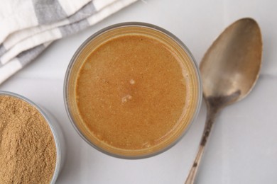 Soluble fiber with water in glass, powder and spoon on white table, top view