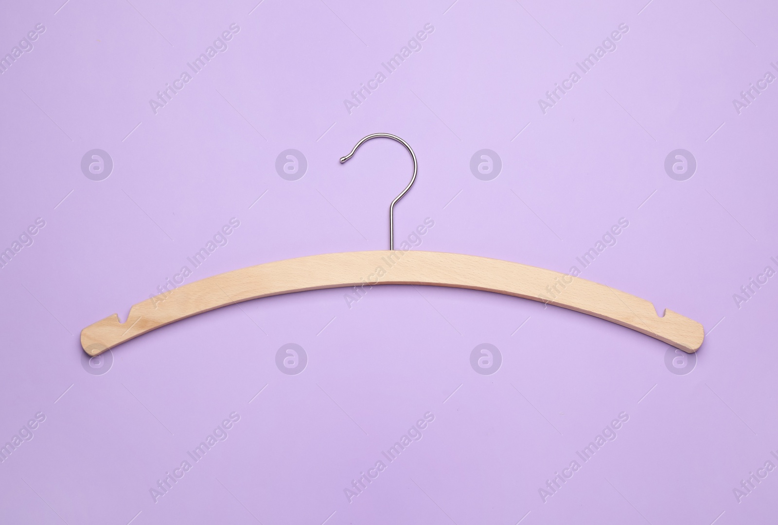 Photo of Empty hanger on lilac background, top view