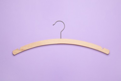 Photo of Empty hanger on lilac background, top view