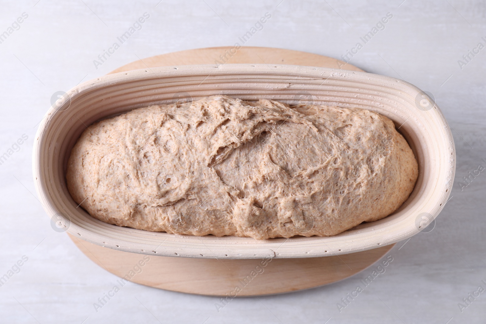 Photo of Fresh sourdough in proofing basket on light table, top view