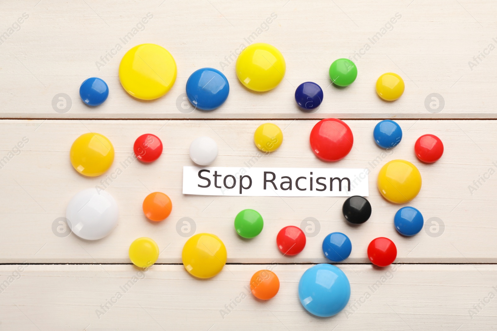 Photo of Phrase Stop Racism and colorful magnets on white wooden table, flat lay
