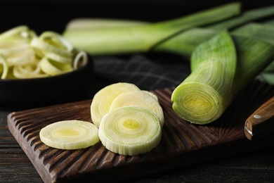 Photo of Fresh raw leeks on black wooden table. Closeup view of ripe onion