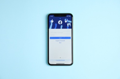 Photo of MYKOLAIV, UKRAINE - JULY 10, 2020: Iphone 11 with Facebook app on light blue background, top view