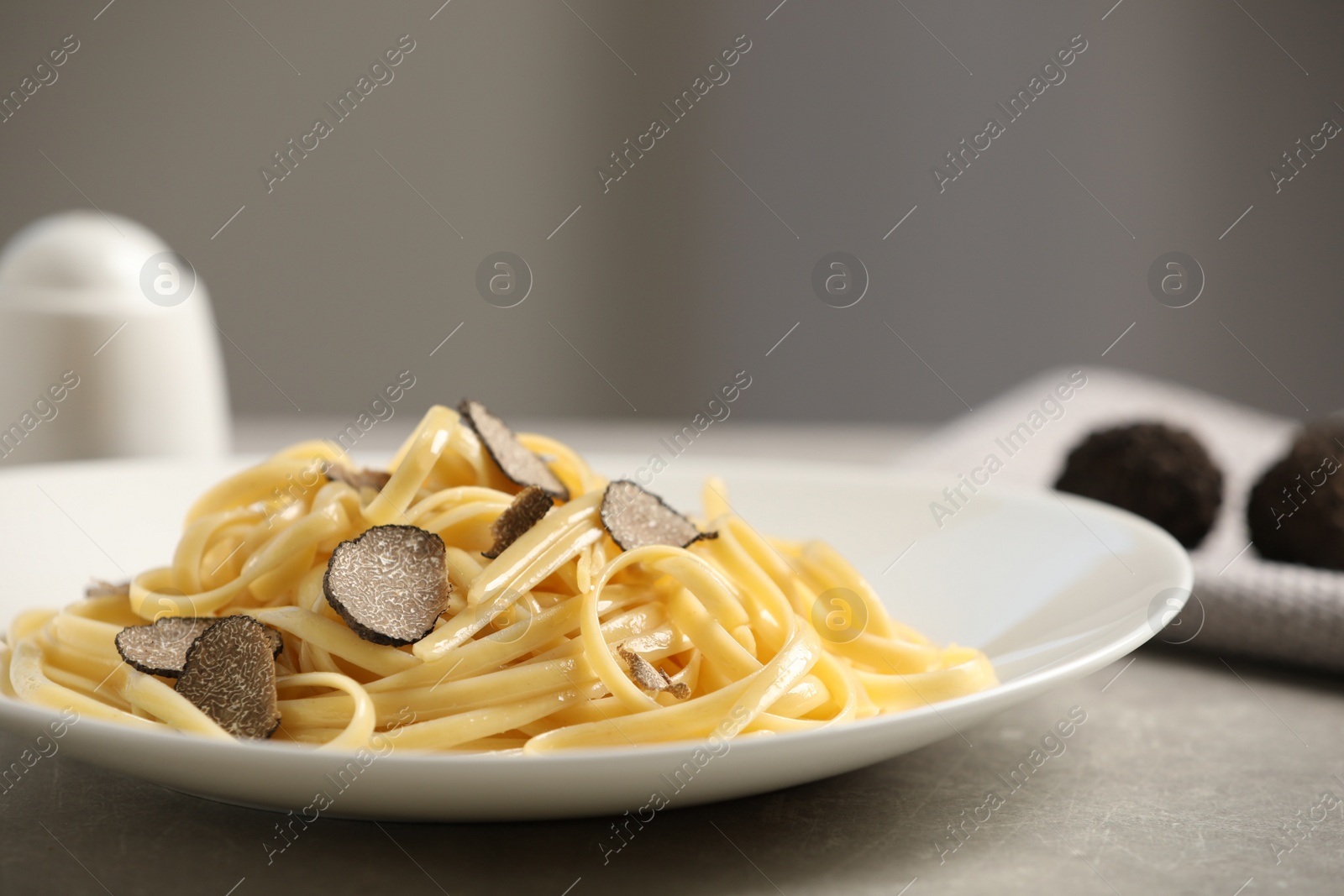 Photo of Tasty fettuccine with truffle on grey table, closeup