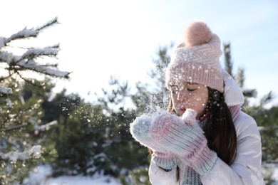Photo of Cute little girl playing with snow in winter forest