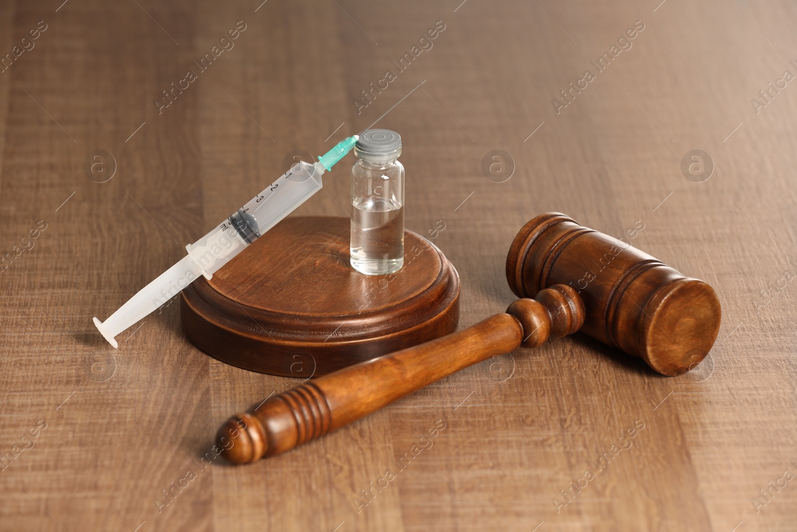 Photo of Law concept. Gavel, syringe and glass vial on wooden table