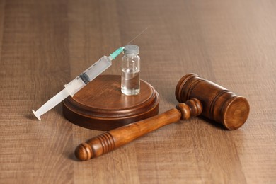 Law concept. Gavel, syringe and glass vial on wooden table