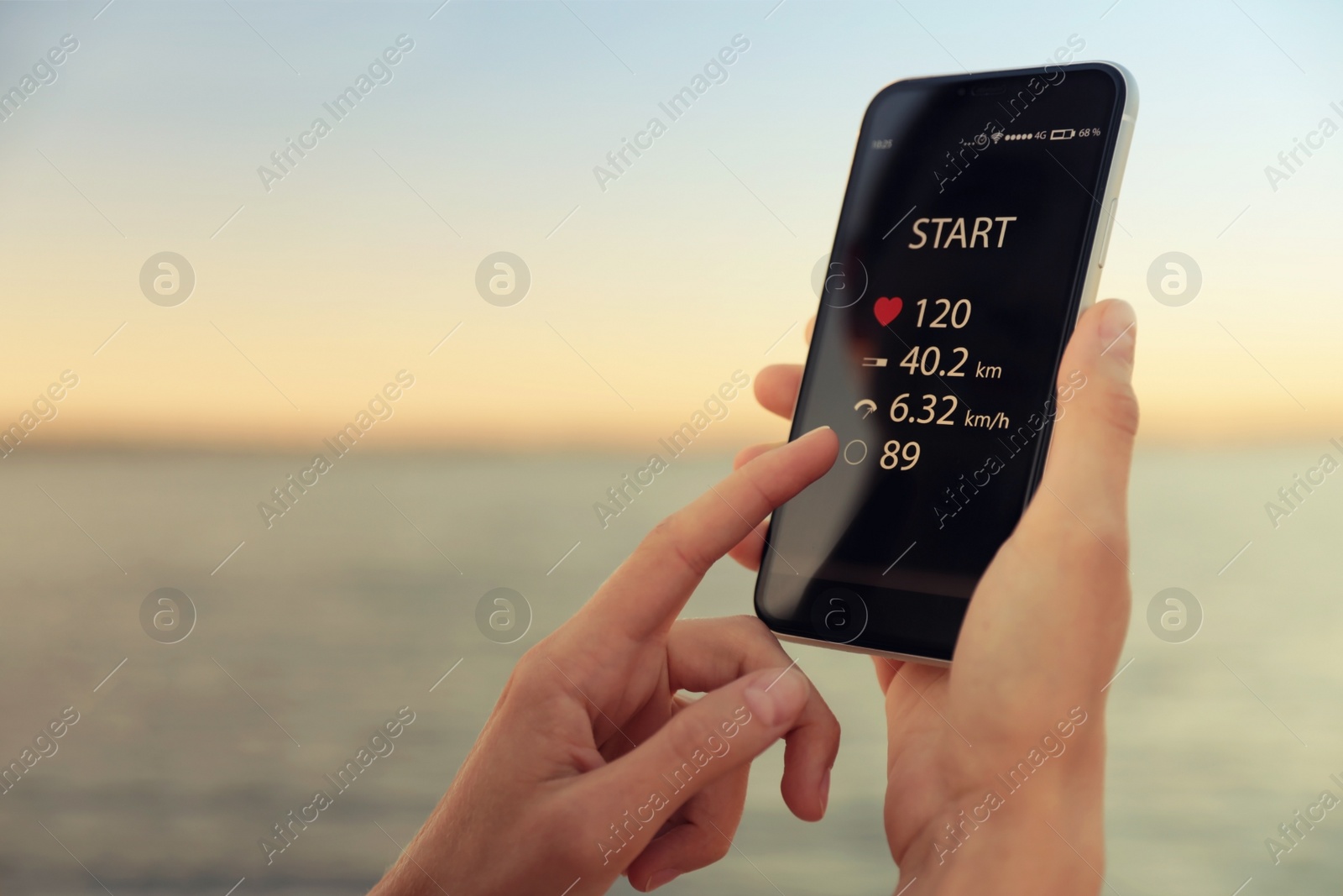 Photo of Young woman using fitness app on smartphone near river at sunset, closeup