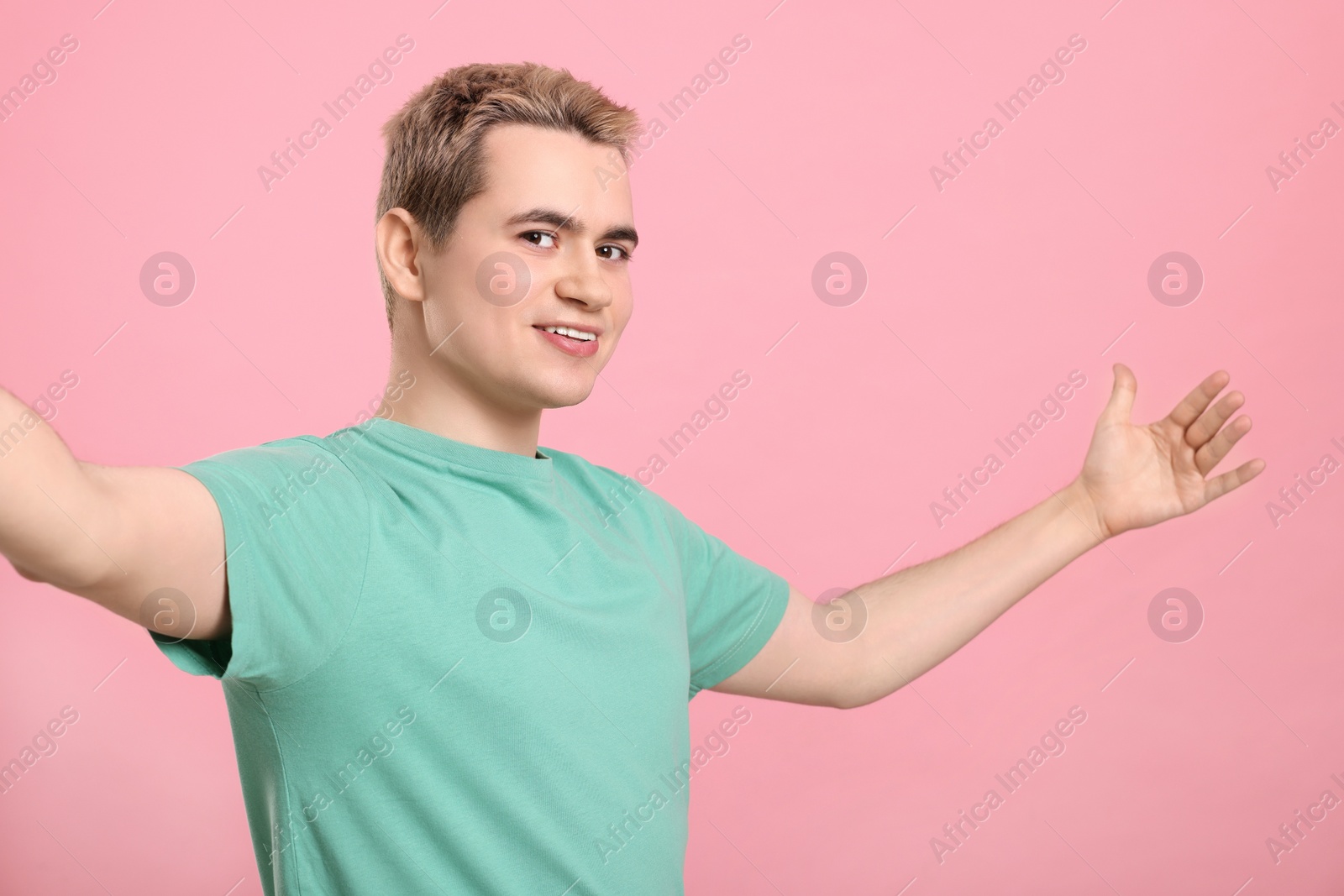 Photo of Happy man inviting to come in against pink background