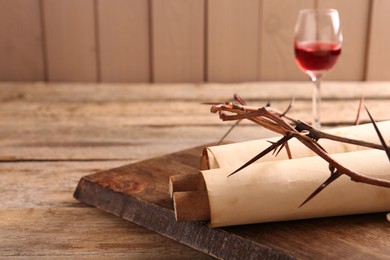 Photo of Crown of thorns, old scrolls and glass with wine on wooden table, selective focus. Space for text