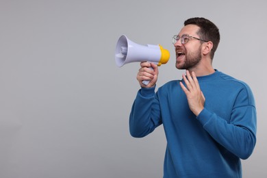 Photo of Special promotion. Man shouting in megaphone on light grey background. Space for text