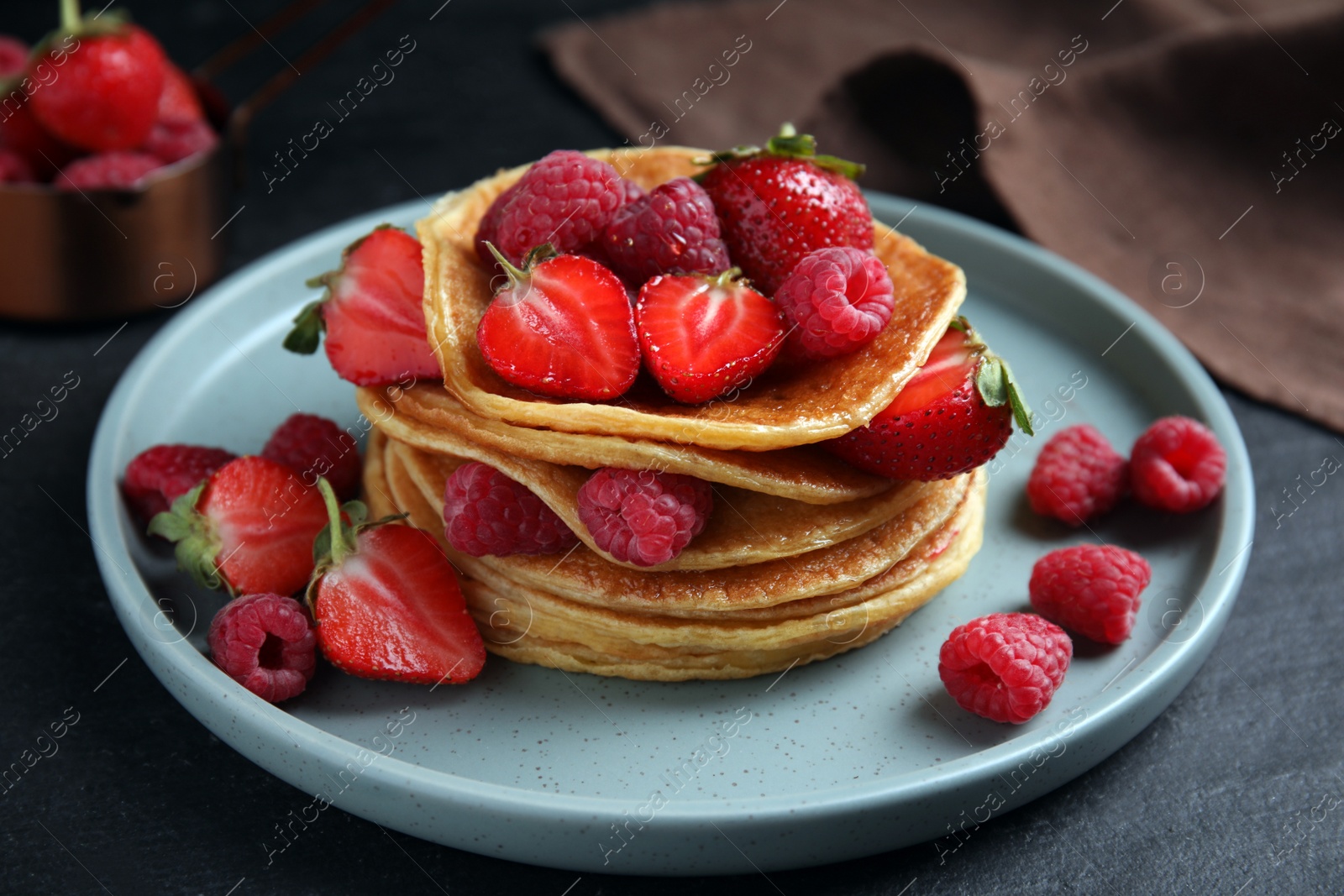 Photo of Tasty pancakes with fresh berries on black table, closeup
