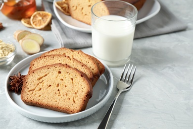 Slices of delicious gingerbread cake served with milk on light grey table