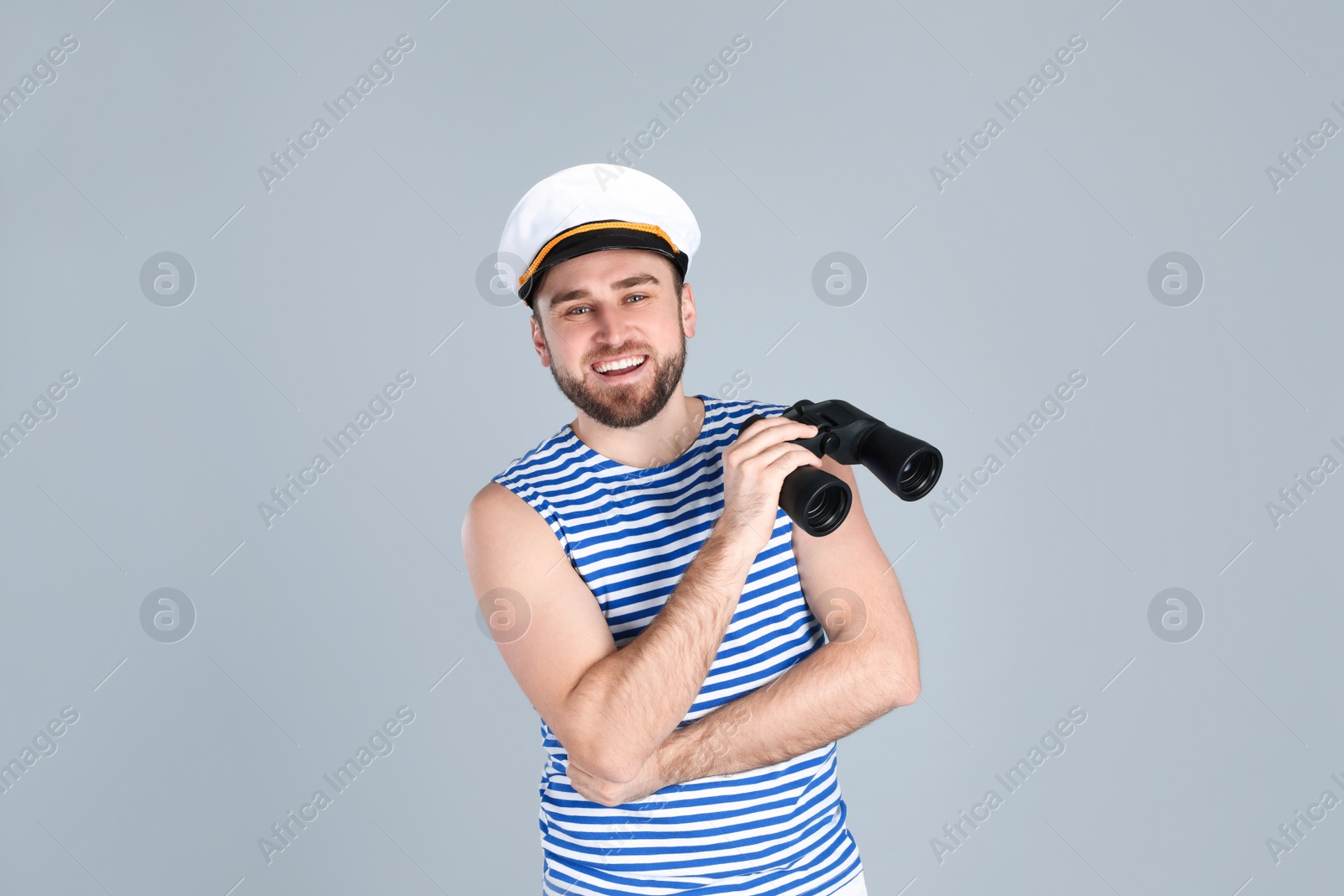 Photo of Happy sailor with binoculars on light grey background