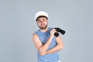 Photo of Happy sailor with binoculars on light grey background