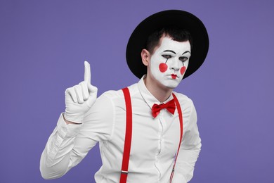 Funny mime artist gesturing on purple background