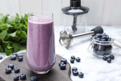 Photo of Glass of blueberry smoothie with mint and fresh berries on white marble table. Space for text