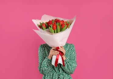 Photo of Woman with red tulip bouquet on pink background. 8th of March celebration