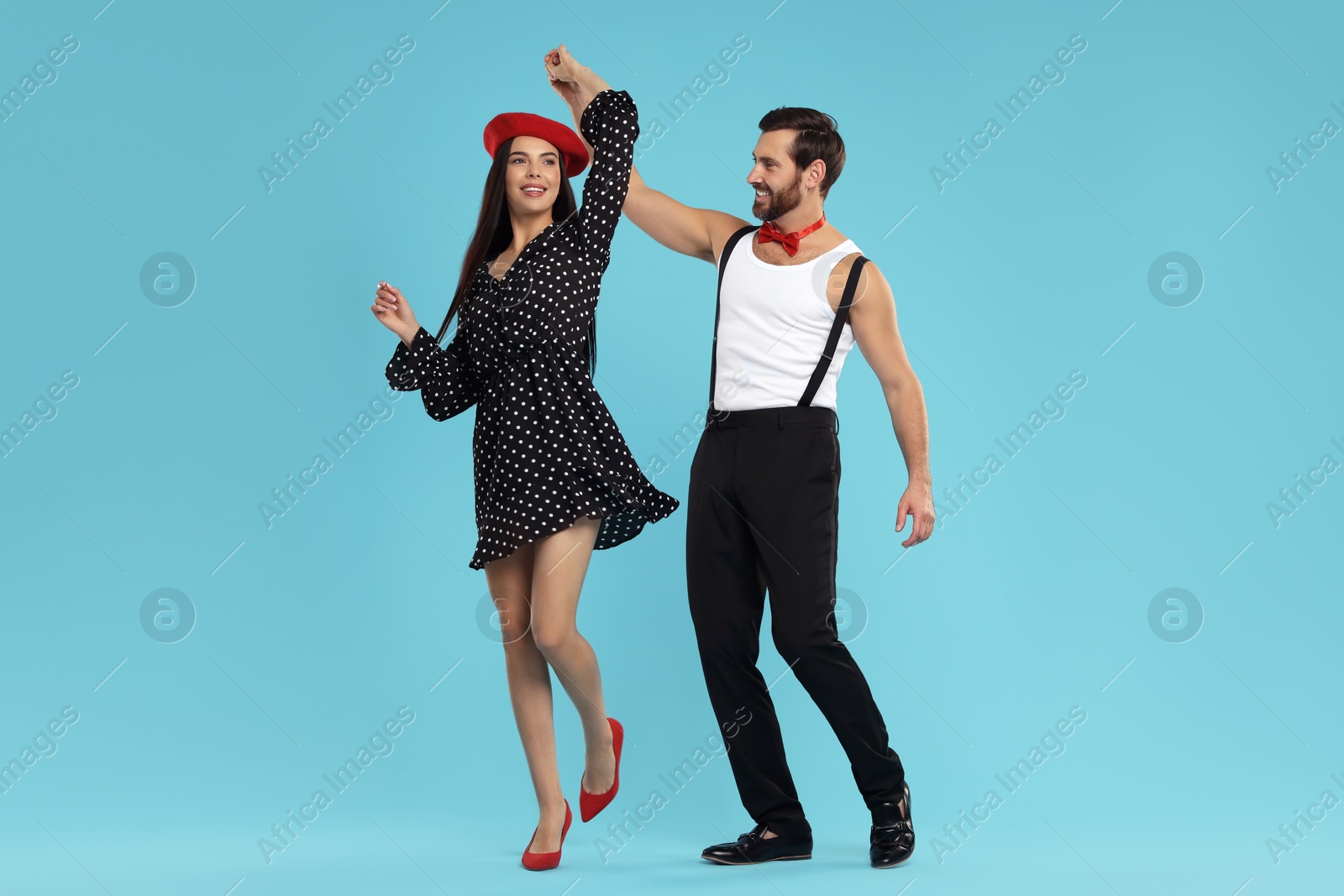 Photo of Happy couple dancing together on light blue background