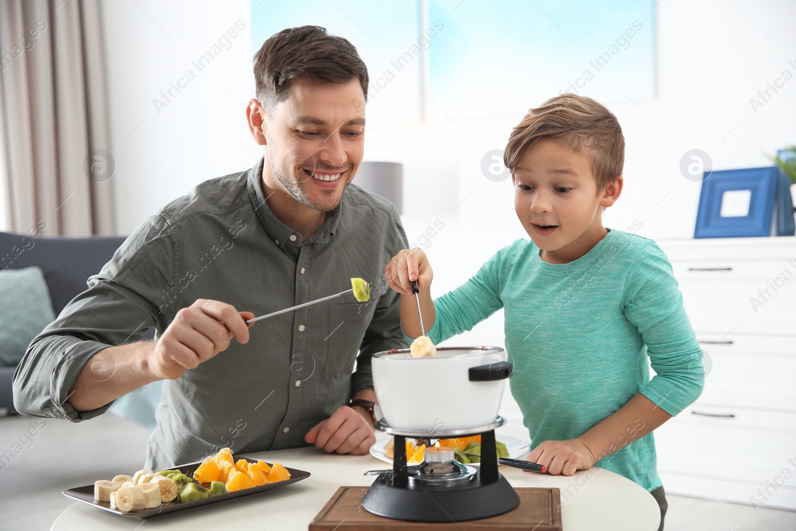 Photo of Father and son enjoying fondue dinner at home