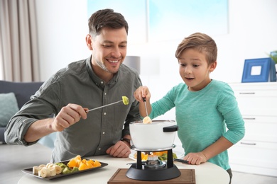 Father and son enjoying fondue dinner at home