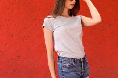 Young woman wearing gray t-shirt near color wall on street